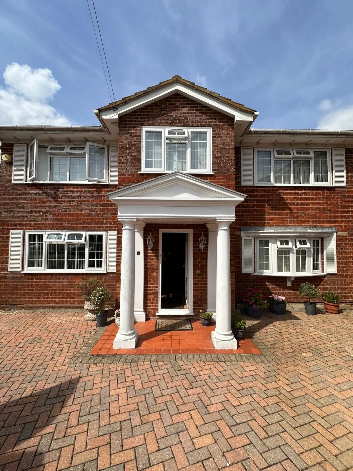 White casements on a red brick house with portico